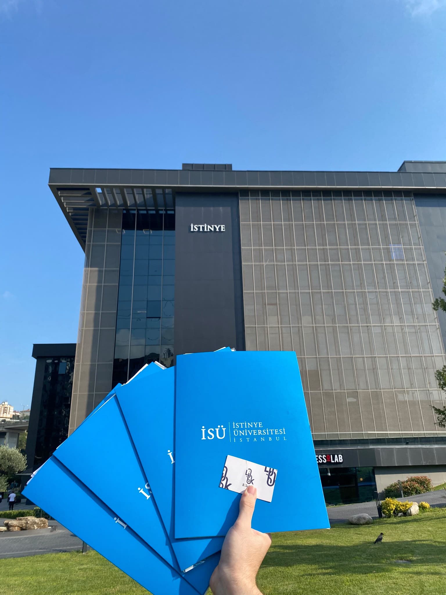 Blue İstinye University folders held outside the campus building